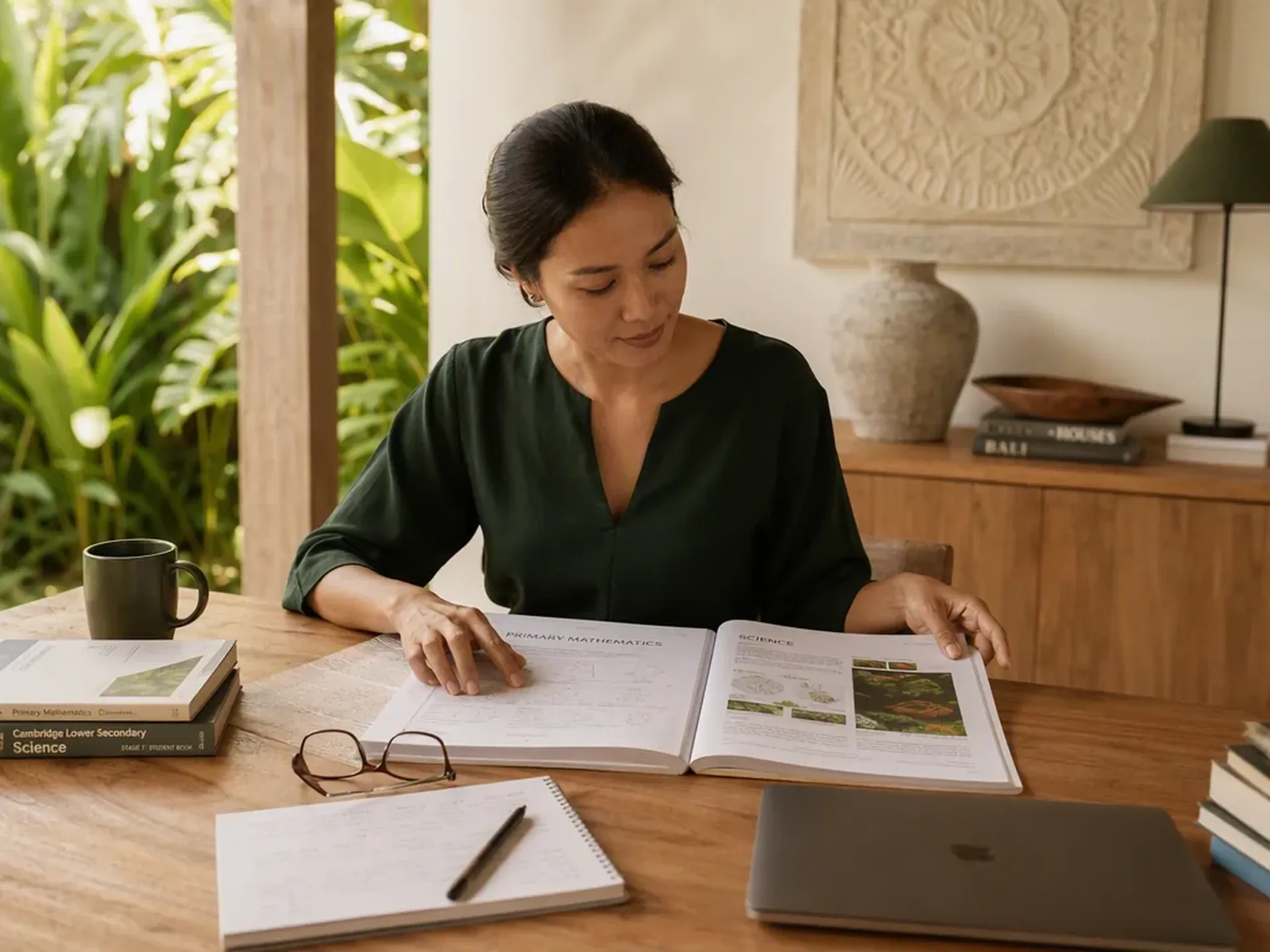 A learner reviewing a science and mathematics book beside a laptop. Illustrative study scene, not a Dyatmika classroom.